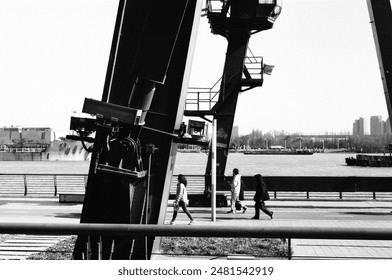 A monochrome image of individuals strolling by a dock - Powered by Shutterstock