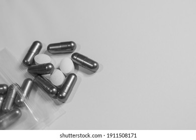 Monochrome immage of many pills on the table.