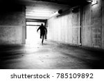 Monochrome of a man fleeing a grungy underground parking. 