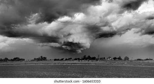 Monochrome Of Ominous And Menacing Looking Funnel Cloud On A Stormy Day Over The Populated Area