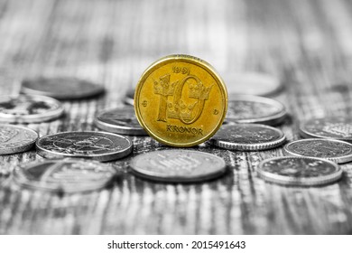 Monochrome photo of various coins and yellow kronor coin in a middle