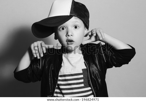 monochrome portrait\
of Funny little boy.Hip-Hop Style. fashion children.handsome.Boy in\
Tracker Hat. Young Rapper. Funny Child in Cap. 4 years old.\
Surprised emotion