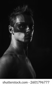 Monochrome portrait of a man with face paint stripe in shadows. for theatrical promotions, music album covers, artistic projects, and modern fashion campaigns.