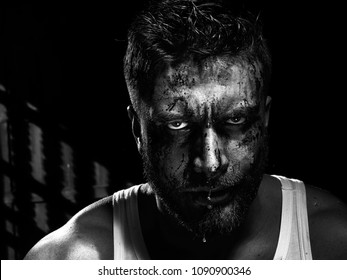 Monochrome portrait of a strong man with a beard, face in blood. He looks at the camera with different emotions. Blood and sweat dripping down his face.