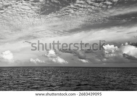 Monochrome seascape with dramatic cloudscape over calm ocean horizon. Perfect for website hero headers, minimalist wall art, editorial layouts, luxury travel branding, and contemporary design projects
