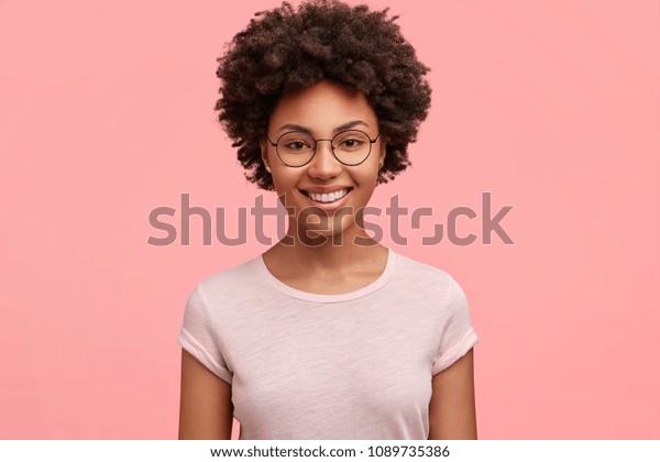 ピンクの壁の上に 元気なアフリカ系アメリカ人ビジネスマンが笑顔で 縮れた黒髪で 疲れ果てた1週間の後 週末を楽しみ 休息も楽しめる の写真素材 今すぐ編集
