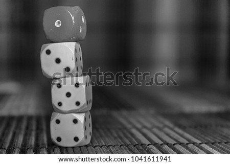 Monochrome Stack of three white plastic dices and one red dice on brown wooden board background. Six sides cube with black dots. Number 1, 3, 4, 5.