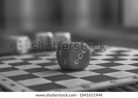 Monochrome Stack of three white plastic dices and one red dice on brown wooden board background. Six sides cube with black dots. Number 3, 2.