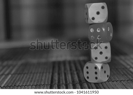Monochrome Stack of three white plastic dices and one red dice on brown wooden board background. Six sides cube with black dots. Number 3, 4, 5, 6