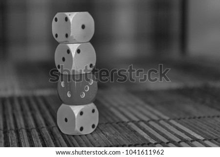 Monochrome Stack of three white plastic dices and one red dice on brown wooden board background. Six sides cube with black dots. Number 1, 2, 3 ,4