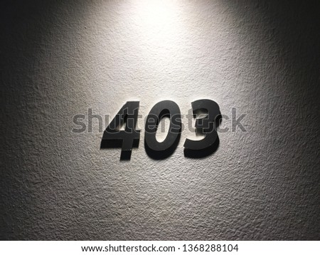 A monochrome top-lit shot of the number 403 (four zero three) on a textured wall as a background. Image has copy space.