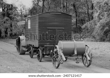 Monochrome. Vintage traction engine road roller with living van and water bowser. Industrial heritage steam.