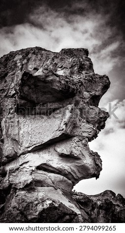 A monolithic rock formation in a dramatic, moody sky.
