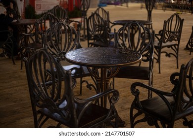 Monolithic Table Made Of Metal. Forged Furniture For An Outdoor Cafe. Dining Place In The City. Beautiful Metal Furniture Table And Chairs. A Piece Of Interior. Steel Product.