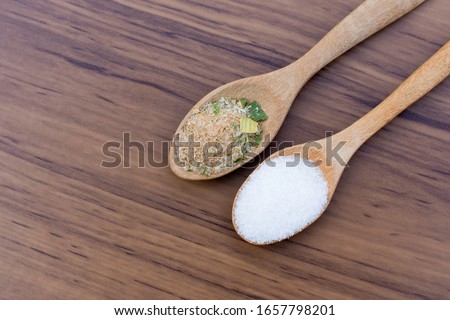 Monosodium glutamate (MSG ) and ingredients in wooden spoon isolated on the wood table background. Top view. Flat lay. 