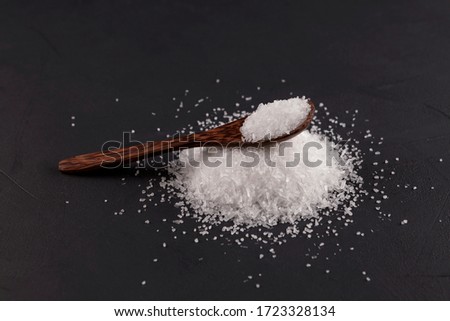 Monosodium glutamate (Msg) in a wooden spoon on a dark background. Food supplement E621. Taste seasoning to enhance the food experience. The additive is used in the food industry.