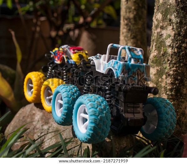 Monster car toys\
standing on stone and grass. Vehicles toy. Simple cheap toys for\
children, kids playing car, abstract concept nobody. Bogor, 07\
Agustus 2022, Indonesia