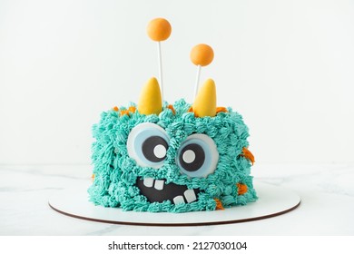 Monster theme cake on the white background. Birthday cake with turquoise fluffy cream cheese frosting