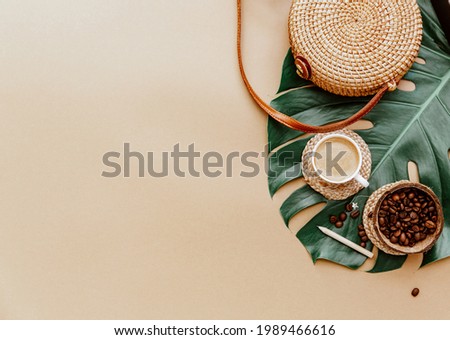 Monstera leaf ,coffee cup and Ratan bag on brown background. Copy space. summer minimal background flat lay, view from top