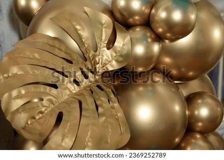 Monstera leaves creatively arranged on golden bombs.Floral composition with golden Christmas balls on golden Monstera.Floral and natural horizontal decoration.