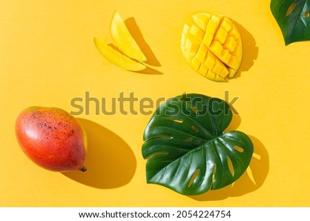 Monstera leaves with mango on a yellow background. Flat lay, top view, close up. Healthy food concept, dieting. Food background. Summer concept
