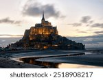 Mont Saint Michel at dusk. Low tide and wind moving the clouds; movement captured by shutter speed. Normandy.