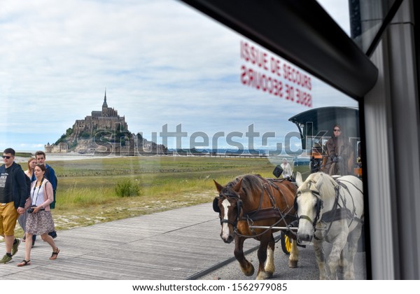 MONT SAINT-MICHEL, FRANCE - JULY 3, 2017:\
Tourists can choose different means of transportation, walking, bus\
or horse-drawn carriage. It is not possible to arrive by car to\
Mont Saint-Michel