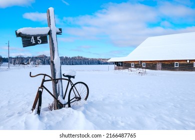 Mont Tremblant, Qc, Canada - January 18th 2021: View On An Old Bicycle, A Mail Box, A Street Sign And An Old Barn, All Covered By The Snow On A Clear Winter Day In Quebec, Canada