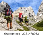 Montage of three hikers and southern side of marmolada, Alps Dolomites mountains, Italy