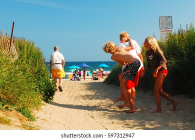 Montauk, NY, USA July 27 Two Kids Rough House With A Teenager On The Path Leading To The Ocean At Ditch Plains Beach In Montauk, New York