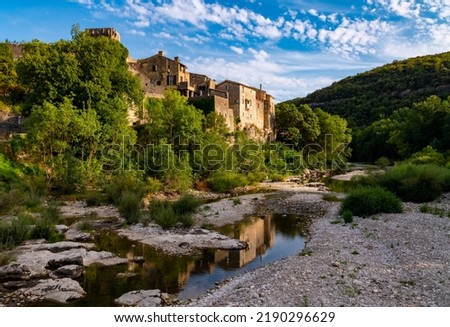 Montclus in C`eze valley near Avignon and Ardèche canyon is a popular historic village with castle. Scenery seen from river bridge with low water on a hot summer evening before sunset on a summer day.