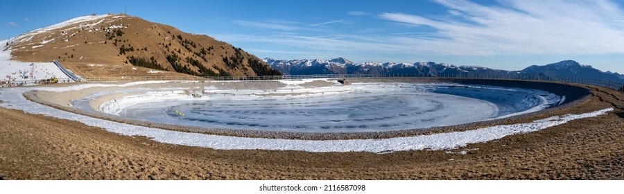 Monte Pora, Italy. Artificial water catchment reservoir for snow skiing slopes. Winter time. Frozen lake