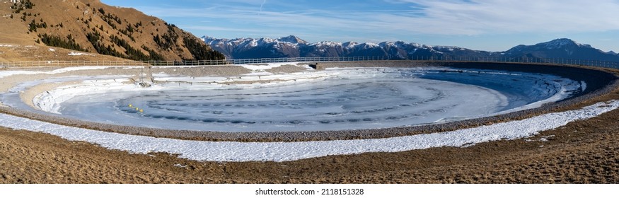 Monte Pora, Italy. Artificial water catchment reservoir for snow skiing slopes. Winter time. Frozen lake