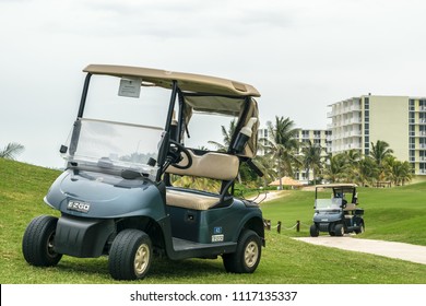 Montego Bay, Jamaica - June 03 2015: Two Empty Golf Carts Parked On The Cinnamon Hill Golf Course In Montego Bay, Jamaica, With Hilton Hotel Resort & Spa In The Background.