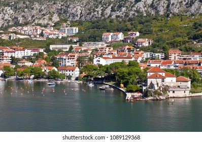 Montenegro. Gulf Of Kotor. Top View On The Picturesque Coastal Town Of Dobrota, The Institute Of Marine Biology And The Old Small  St. Ilijah Church