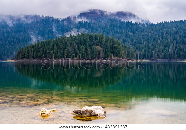 モンテネグロ 緑の木を反映した デュルミトール国立公園の自然の風景にある黒い湖の静かなガラス質の透明な水 の写真素材 今すぐ編集
