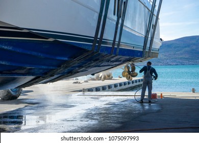 Montenegro, Tivat, October 30 2017. Man is working at the Navar Boatyard. He is using a pressure washer to clean the bottom of the boat while it is in dry dock. He is removing barnacles.