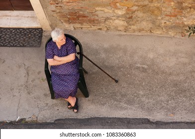 Montepulciano / Italy - August 11 2009: Old Italian Mad Or Grumpy Lady Sitting In Chair On The Street.