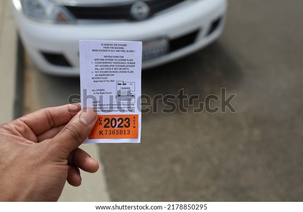 Monterey,
California, USA - July 15, 2022: African-American man holding 2023
car registration in front of white
car