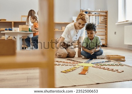 montessori material, african american boy playing educational color game near cheerful teacher, kids
