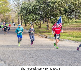 MONTGOMERY, ALABAMA - MARCH 10, 2018:  2018 Montgomery Half Marathon and 5k:  Mature Marine bears the United States Flag to honor a fallen soldier shown on tee shirt back as he hits the halfway mark.