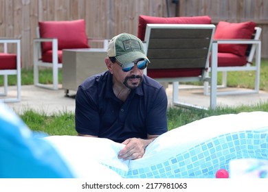 Montgomery County, TN, USA - June 2022: A Tired Looking Man In Sunglasses Fills Up A Kiddie Pool On A Sweltering Summer Day In Middle Tennessee