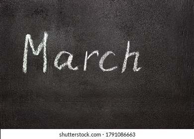 Month written in white chalk on a chalkboard. The month depicted on the chalkboard is March