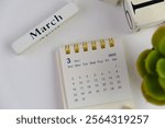 Monthly desk calendar for MARCH 2025 on an office background. 