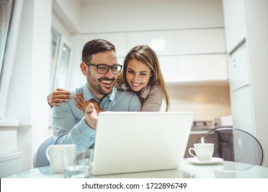 The monthly finances. Couple doing their finances at home. They drinking first coffee of the day at the kitchen. Making online time, bonding time. Young couple using a laptop together at home - Powered by Shutterstock