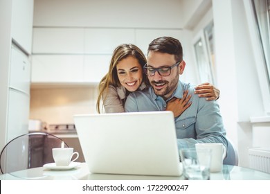 The monthly finances. Young couple doing their finances at home. They drinking first coffee of the day at the kitchen. Making online time, bonding time. Young couple using a laptop together at home