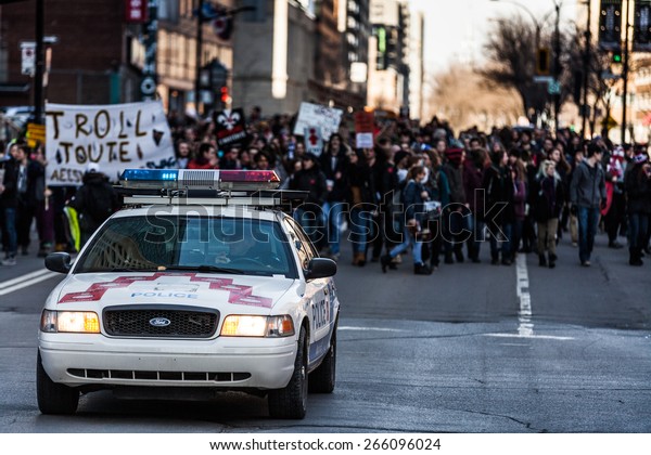 MONTREAL, CANADA   APRIL 02 2015:\
Riot in the Montreal Streets to counter the Economic Austerity\
Measures. Police Car in front of the Protesters controlling the\
Traffic