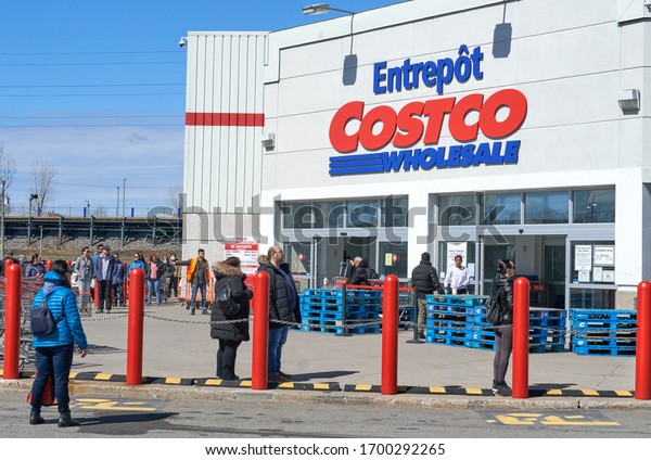 Montreal,\
Canada - April 4. 2020: People with masks in a line to enter Costco\
Wholesale. Many stores implemented social distancing which caused\
lines to enter to the shop due to\
Coronavirus