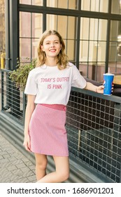 Montreal, Canada - June 15 2018: Girl Young Hipster Blogger In White T-shirt And Pink Skirt Posing With Pepsi Cup. City Street Cafe On Background