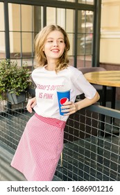 Montreal, Canada - June 15 2018: Girl Young Hipster Blogger In White T-shirt And Pink Skirt Posing With Pepsi Cup. City Street Cafe On Background